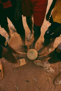 A group of children playing soccer on a dusty field in Nigeria.